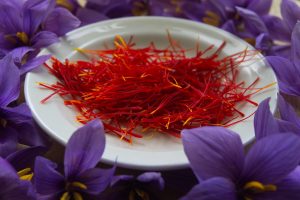 A bowl of red saffron spice among purple flowers