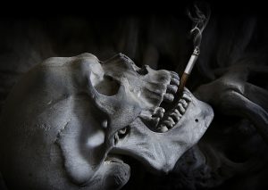 Image of a Skull with a smoking cigarette between its teeth - smoking kills