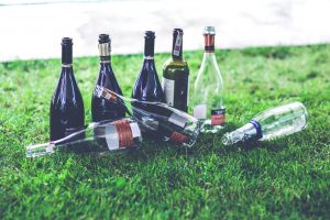 Image of 8 empty wine bottles in the grass