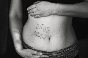 Image of a woman with her shirt pulled up to show "Out of Order" written on her belly